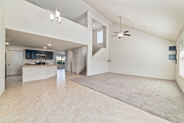 unfurnished living room featuring light carpet, high vaulted ceiling, stairs, and a ceiling fan