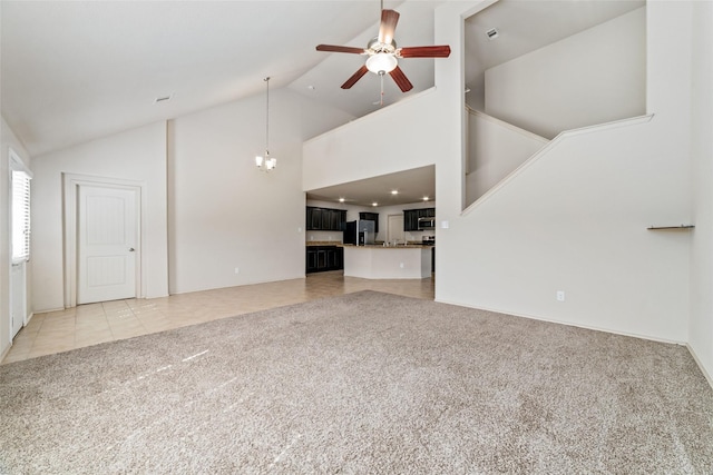 unfurnished living room featuring light tile patterned floors, ceiling fan with notable chandelier, high vaulted ceiling, and light colored carpet