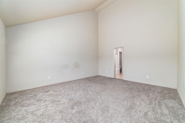 carpeted empty room featuring high vaulted ceiling