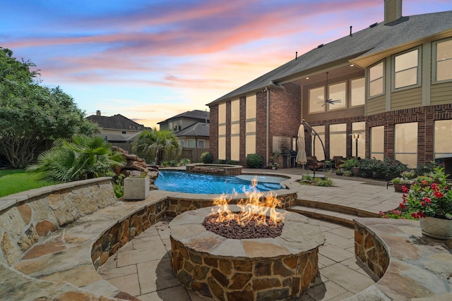 outdoor pool with a patio, fence, a fire pit, and an in ground hot tub