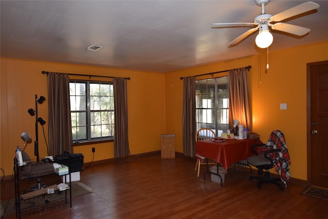 interior space featuring a ceiling fan, visible vents, baseboards, and wood finished floors