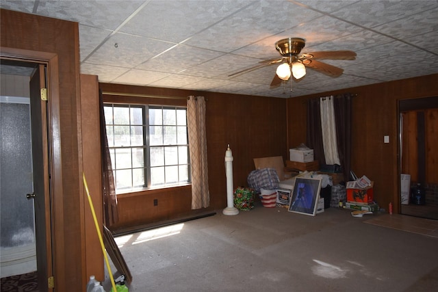 interior space with a ceiling fan and wooden walls