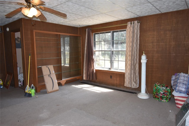 unfurnished room featuring ceiling fan and wooden walls