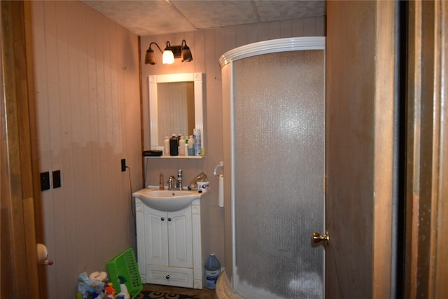 full bathroom with wood walls, a shower stall, and vanity