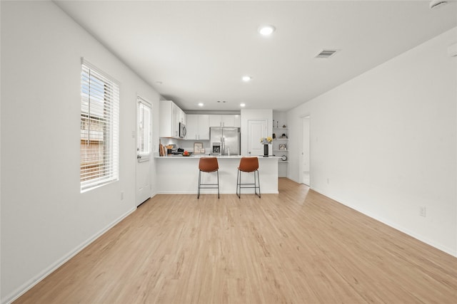 kitchen featuring visible vents, appliances with stainless steel finishes, a peninsula, light countertops, and light wood-style floors