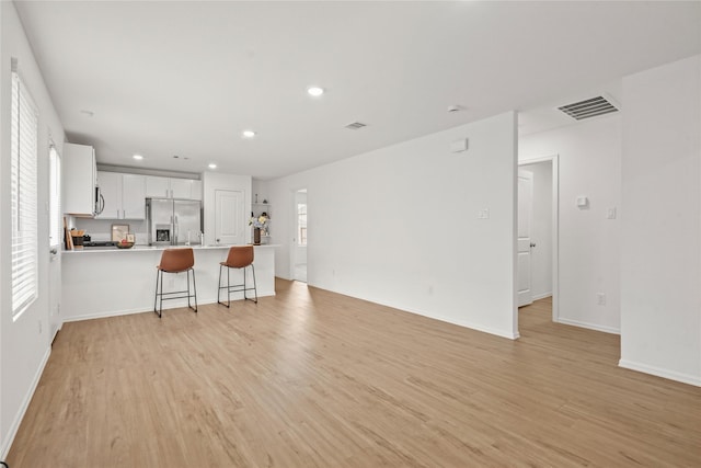 living area featuring recessed lighting, baseboards, visible vents, and light wood finished floors