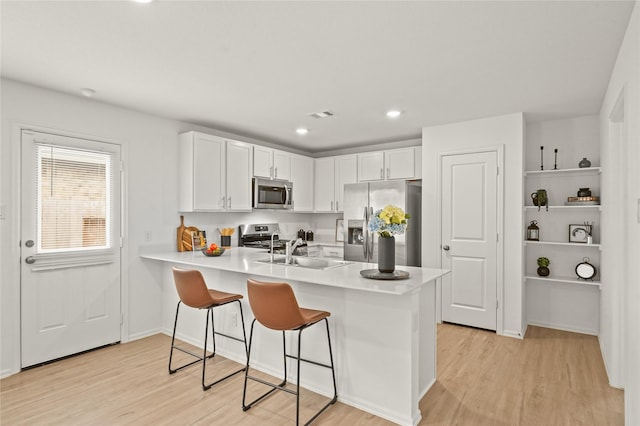 kitchen with stainless steel appliances, a breakfast bar, a peninsula, and light countertops