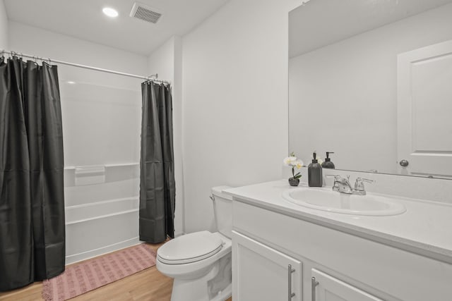 bathroom featuring visible vents, toilet, wood finished floors, shower / bathtub combination with curtain, and vanity