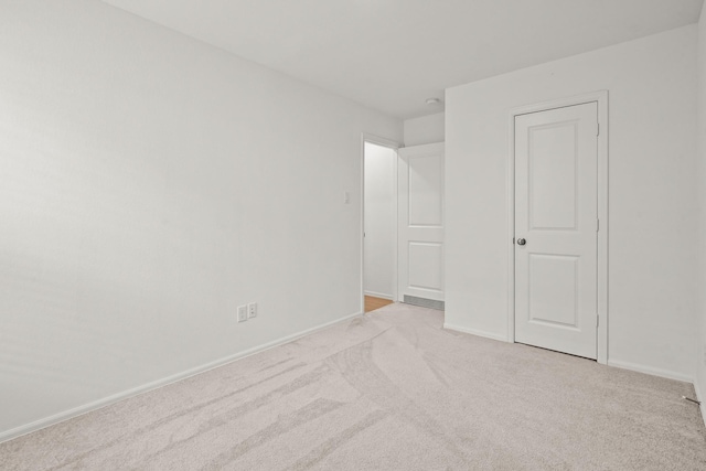 unfurnished bedroom featuring light carpet and baseboards