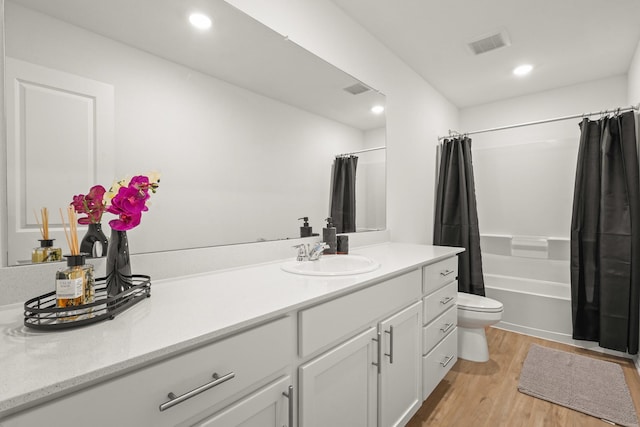 bathroom featuring toilet, recessed lighting, wood finished floors, vanity, and shower / bath combo with shower curtain