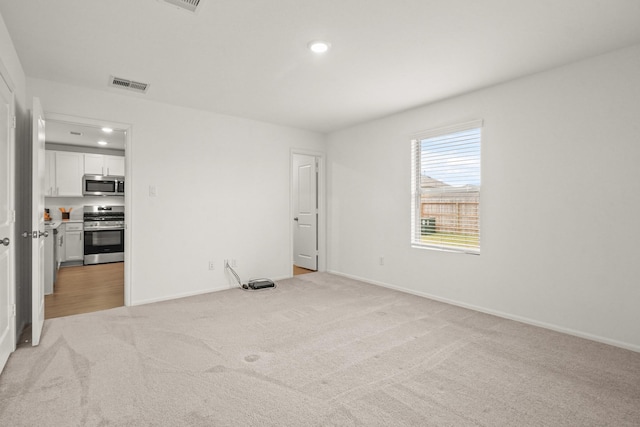 spare room with light colored carpet, visible vents, baseboards, and recessed lighting