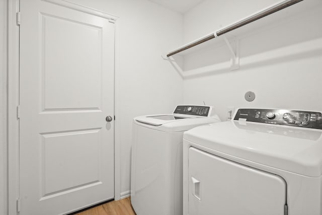 clothes washing area featuring laundry area, light wood-type flooring, and washer and dryer