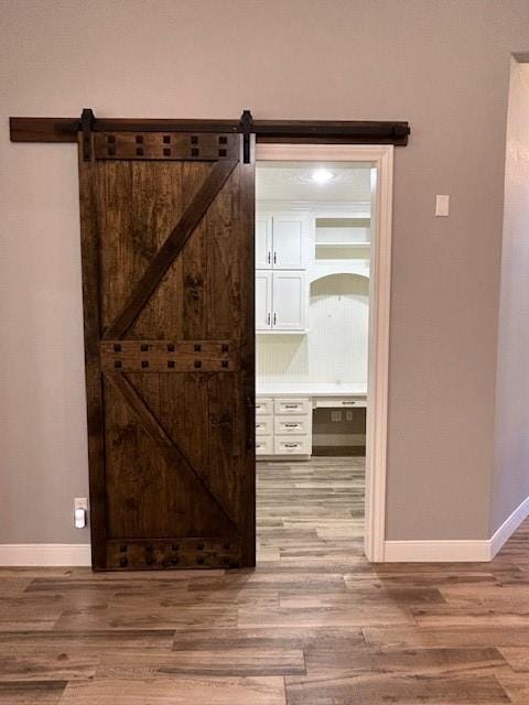 interior space featuring a barn door, wood finished floors, and baseboards