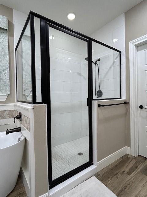 full bathroom with a soaking tub, a shower stall, and wood finished floors