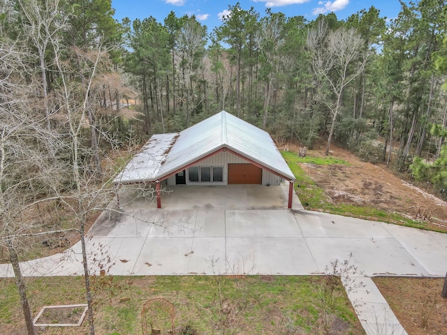 exterior space with a detached garage and a wooded view