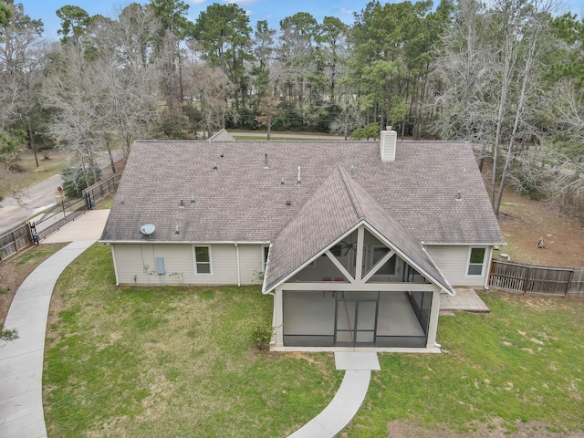 rear view of property featuring roof with shingles, a yard, a chimney, and fence