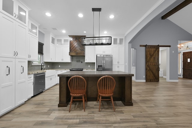 kitchen with arched walkways, a barn door, stainless steel appliances, a kitchen island, and an inviting chandelier