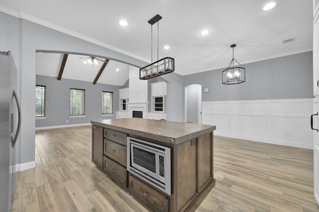 kitchen with arched walkways, a fireplace, open floor plan, appliances with stainless steel finishes, and dark countertops