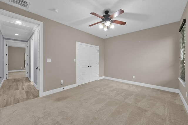 unfurnished bedroom with a closet, light colored carpet, visible vents, a ceiling fan, and baseboards