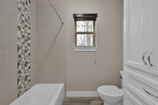 bathroom with shower / bathtub combination, wood finished floors, toilet, and baseboards