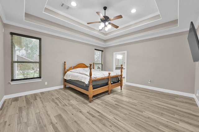 bedroom featuring multiple windows, light wood-type flooring, a raised ceiling, and visible vents