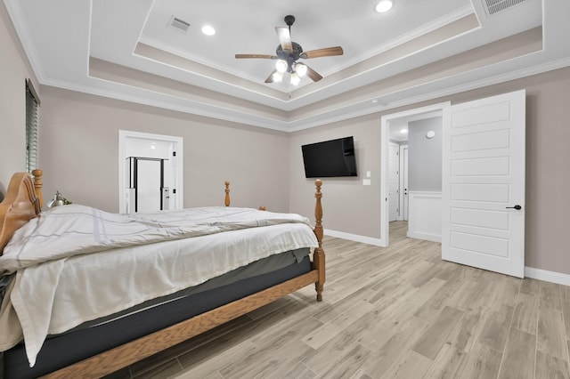 bedroom with light wood-style floors, a tray ceiling, visible vents, and baseboards