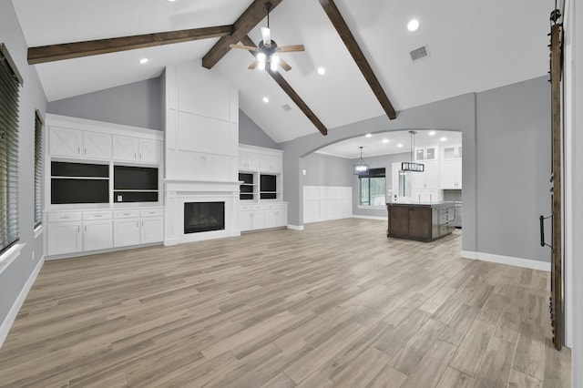 unfurnished living room with a fireplace, visible vents, light wood-style floors, ceiling fan, and high vaulted ceiling