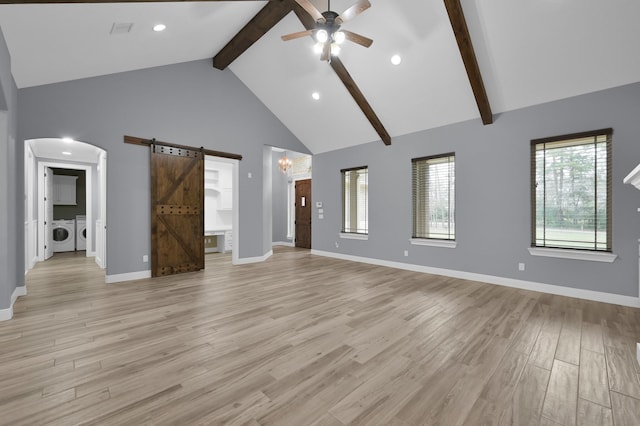 unfurnished living room featuring washer and clothes dryer, a barn door, high vaulted ceiling, light wood-type flooring, and beamed ceiling