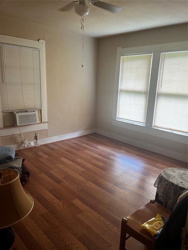 living room with a ceiling fan, baseboards, cooling unit, and wood finished floors