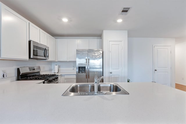 kitchen featuring visible vents, white cabinets, appliances with stainless steel finishes, light countertops, and a sink