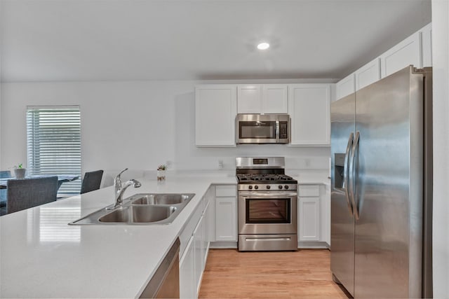 kitchen featuring appliances with stainless steel finishes, light countertops, white cabinets, and a sink