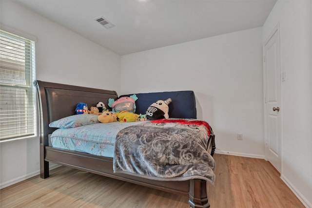 bedroom with baseboards, visible vents, and wood finished floors