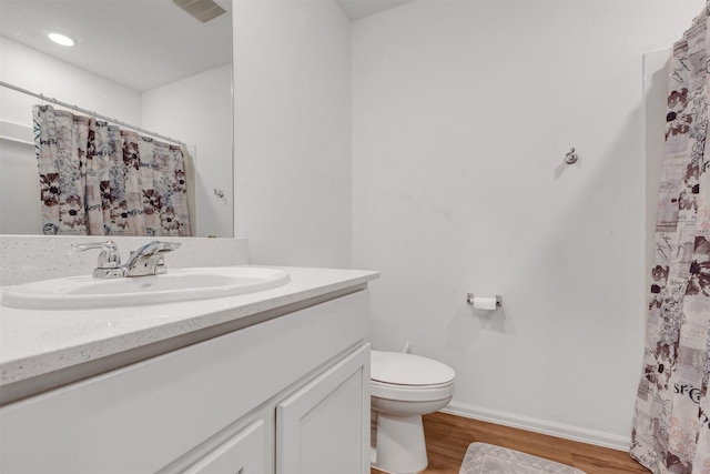 full bath with visible vents, toilet, vanity, wood finished floors, and baseboards