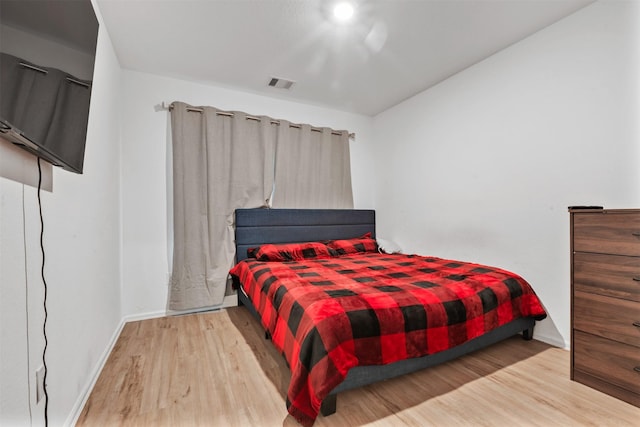 bedroom with wood finished floors, visible vents, and baseboards