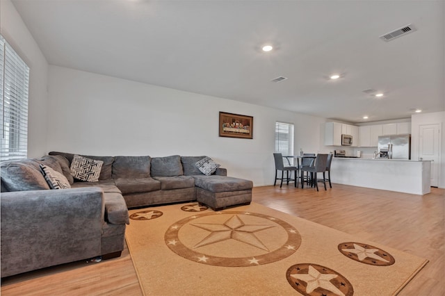 living area with visible vents, light wood-style flooring, and recessed lighting