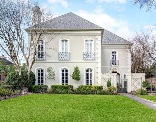 view of front facade featuring a front lawn, a chimney, fence, and stucco siding