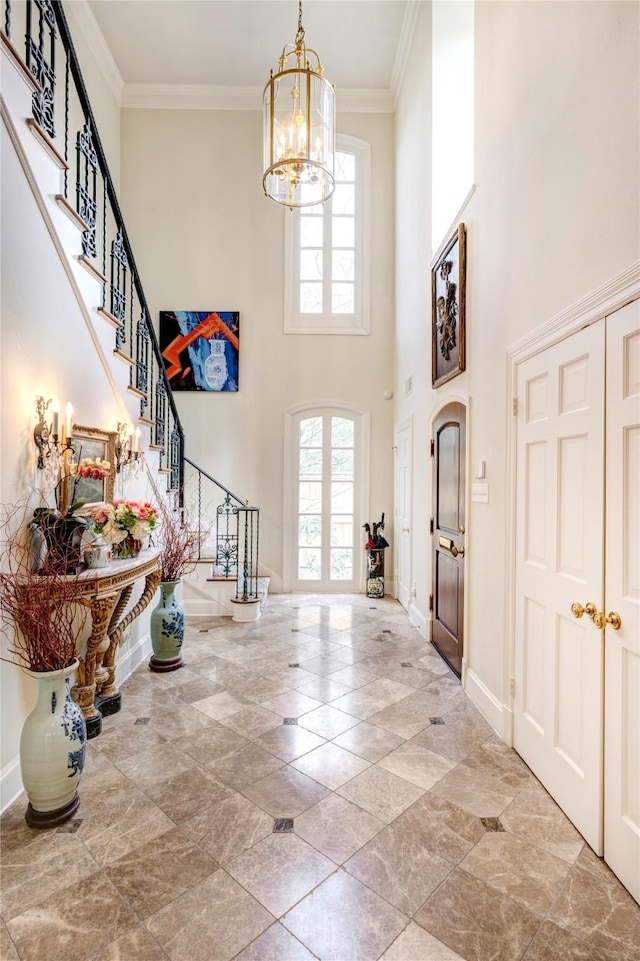 entryway featuring an inviting chandelier, baseboards, stairs, and ornamental molding