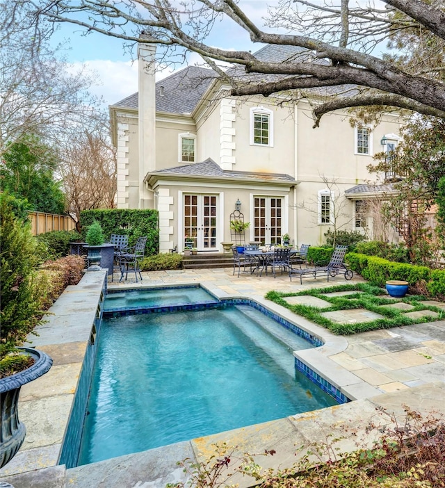 rear view of house with a chimney, fence, french doors, a patio area, and stucco siding