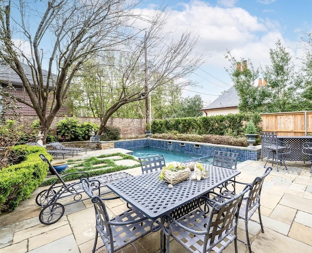 view of patio / terrace featuring outdoor dining space, a fenced backyard, and an outdoor pool