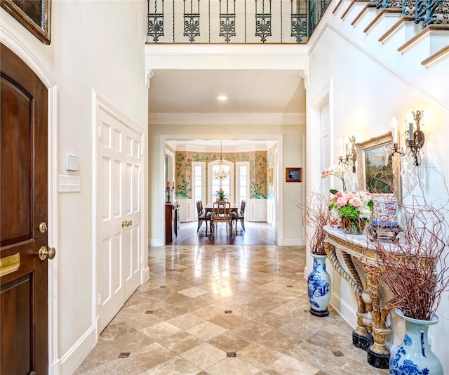 foyer featuring a towering ceiling, baseboards, and crown molding