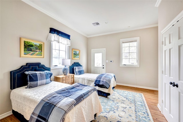 bedroom featuring ornamental molding, multiple windows, and wood finished floors