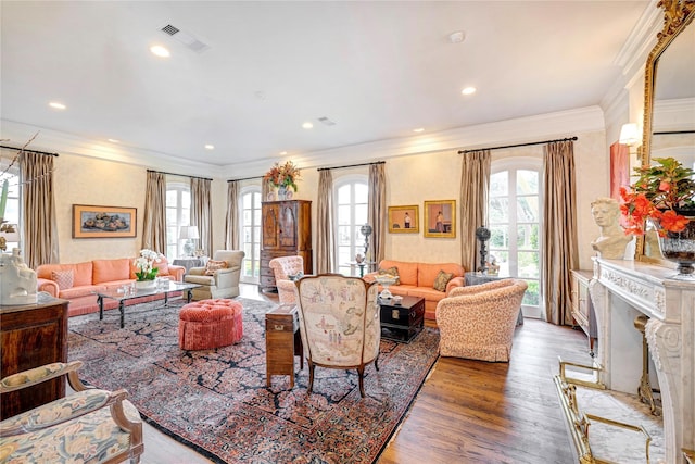 living area with visible vents, wood finished floors, a wealth of natural light, and crown molding