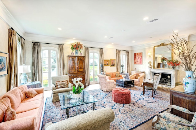 living area with ornamental molding, visible vents, a fireplace, and wood finished floors