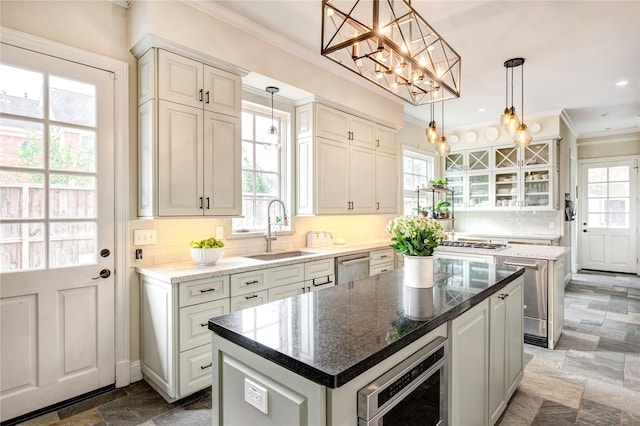 kitchen with a sink, appliances with stainless steel finishes, tasteful backsplash, stone finish floor, and crown molding