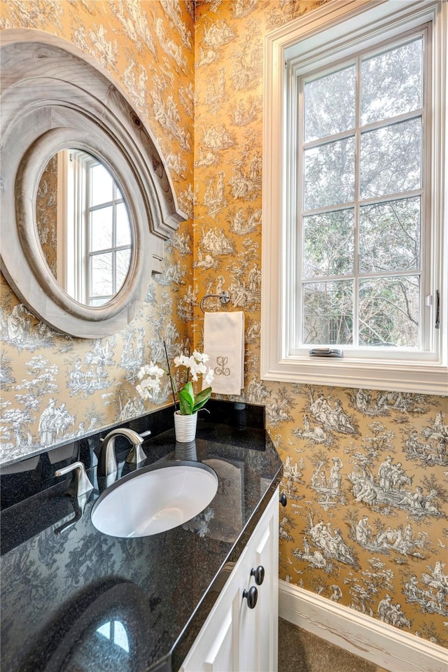 bathroom featuring baseboards, vanity, a wealth of natural light, and wallpapered walls