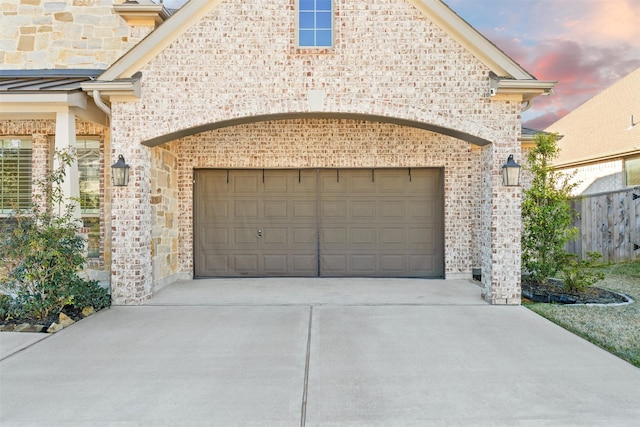 garage at dusk featuring concrete driveway