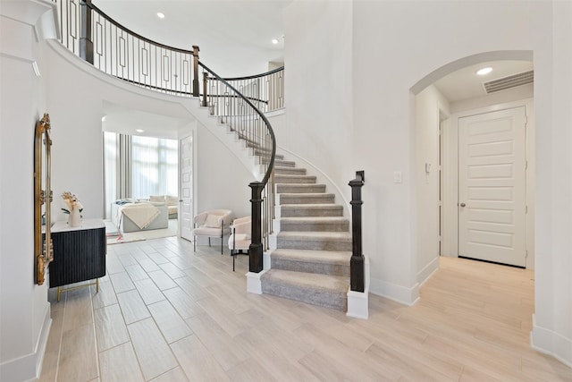 foyer featuring wood tiled floor, visible vents, arched walkways, and baseboards