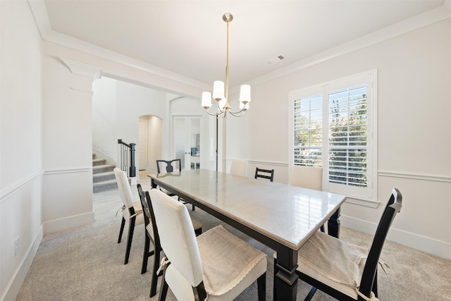 dining space featuring light colored carpet, crown molding, visible vents, and stairs