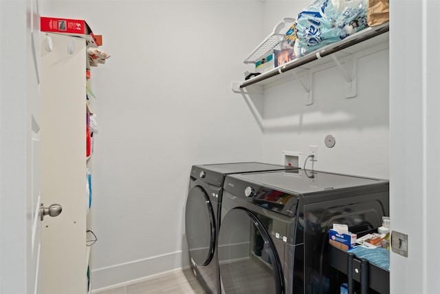 laundry room with laundry area, washing machine and clothes dryer, and baseboards