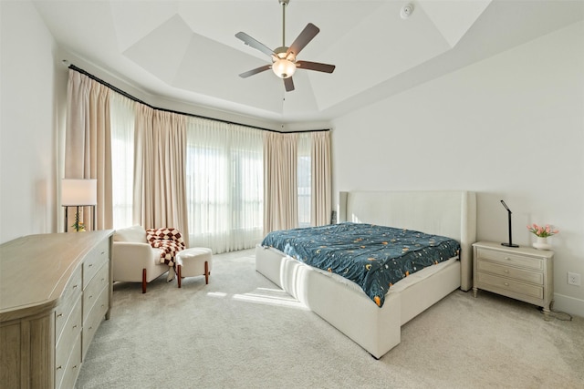 bedroom featuring a raised ceiling, a ceiling fan, and light colored carpet